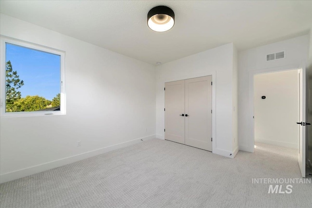 unfurnished bedroom featuring a closet and light colored carpet