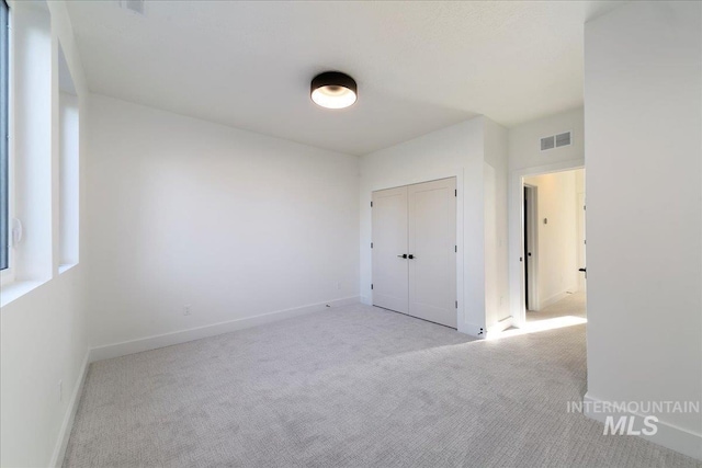 unfurnished bedroom with light carpet and a closet