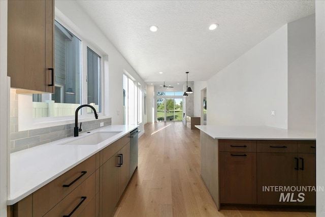 kitchen featuring a textured ceiling, ceiling fan, sink, decorative light fixtures, and light hardwood / wood-style floors