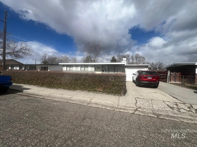 view of front facade featuring a garage, a chimney, and driveway