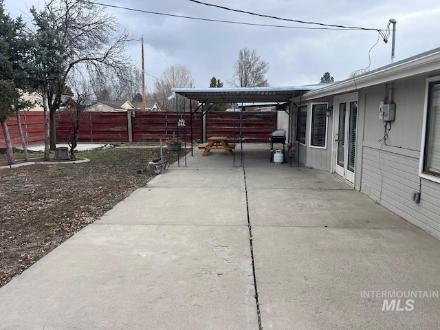 view of patio / terrace with an attached carport, concrete driveway, and fence