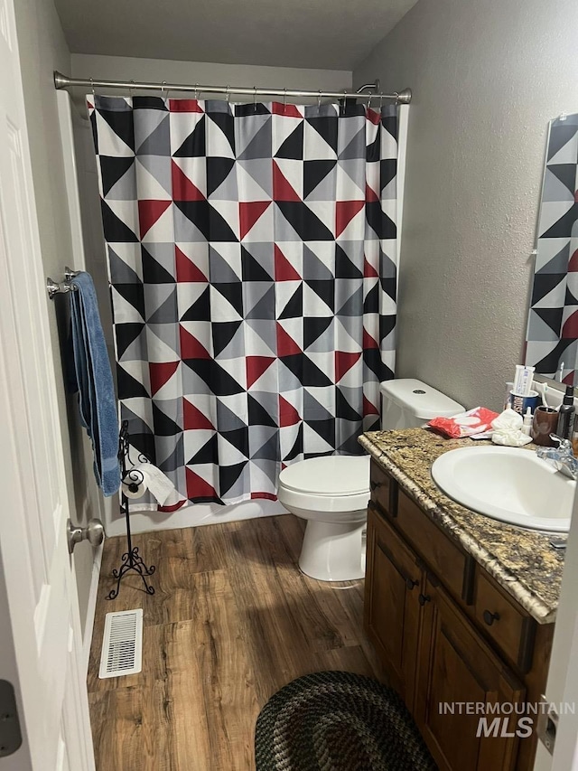 bathroom featuring visible vents, toilet, a shower with shower curtain, wood finished floors, and vanity