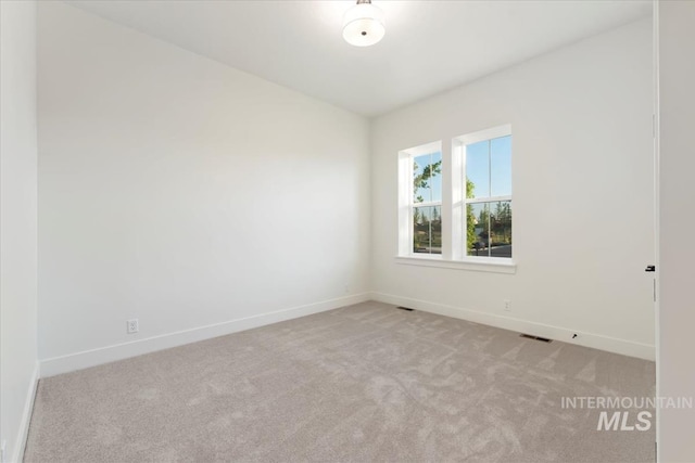 spare room with baseboards, visible vents, and light colored carpet