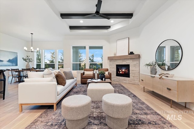 living room featuring beam ceiling, light wood-type flooring, coffered ceiling, ceiling fan with notable chandelier, and a fireplace
