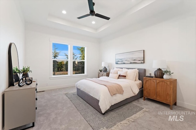 bedroom featuring recessed lighting, a raised ceiling, baseboards, and light carpet