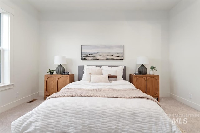bedroom with visible vents, baseboards, and light colored carpet