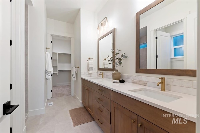 bathroom featuring double vanity, a spacious closet, tile patterned flooring, and a sink