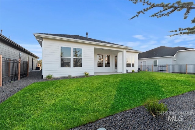 rear view of house with a lawn and a fenced backyard