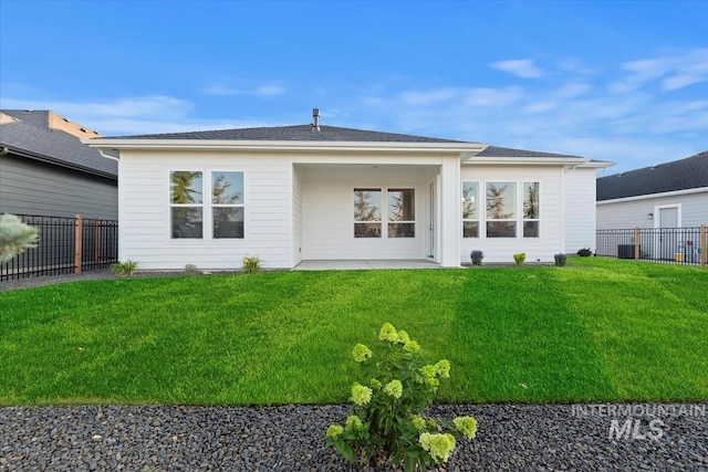 rear view of house with a lawn, a fenced backyard, and a patio area