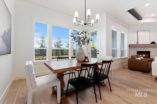 dining room with a fireplace, a chandelier, and light hardwood / wood-style floors