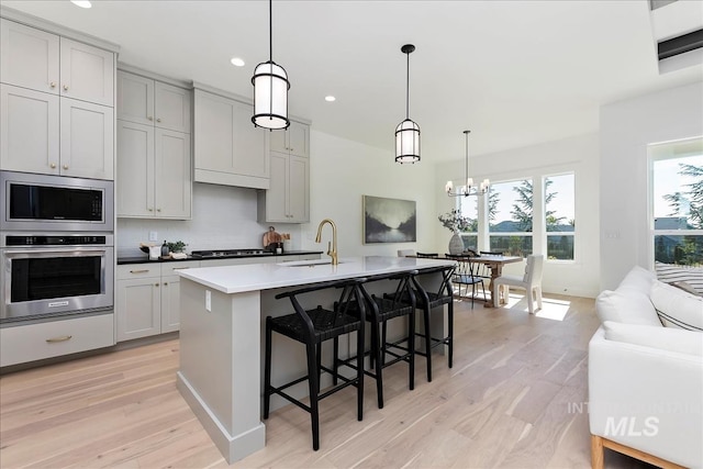 kitchen with recessed lighting, light wood finished floors, stainless steel appliances, and a sink