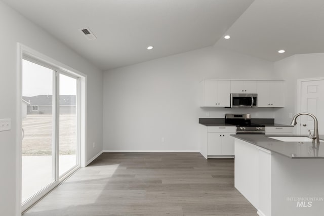 5754 W Stavros St, Meridian, ID 83646 - kitchen with stainless steel appliances, a sink, vaulted ceiling, white cabinetry, and dark countertops