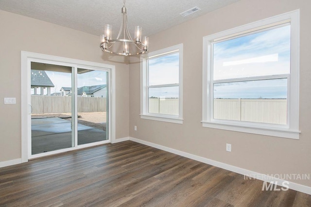 unfurnished dining area featuring dark wood-type flooring, visible vents, and baseboards