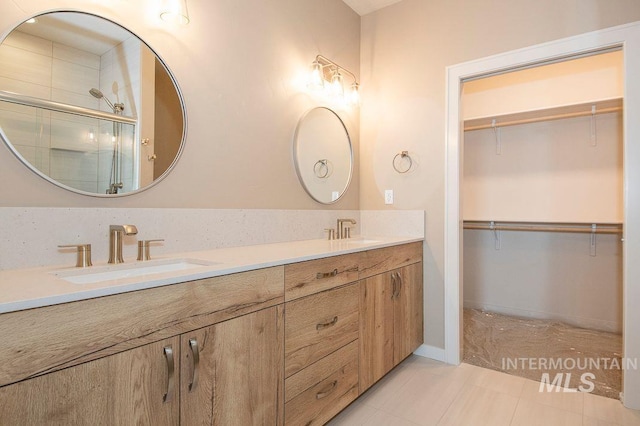 full bathroom with a sink, a walk in closet, and a shower stall