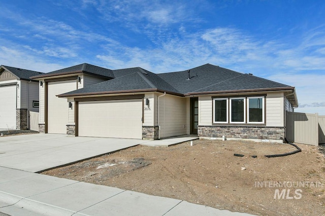 view of front of home with a garage, a shingled roof, concrete driveway, stone siding, and fence