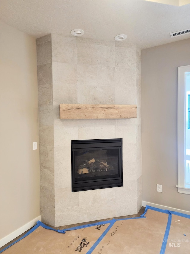 details with baseboards, visible vents, and a tiled fireplace