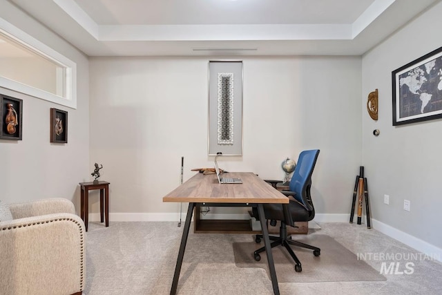 carpeted home office featuring baseboards and a tray ceiling