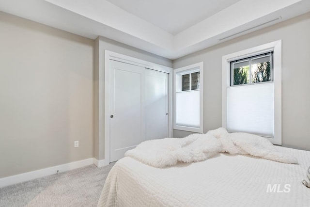 bedroom featuring baseboards, a closet, and light colored carpet