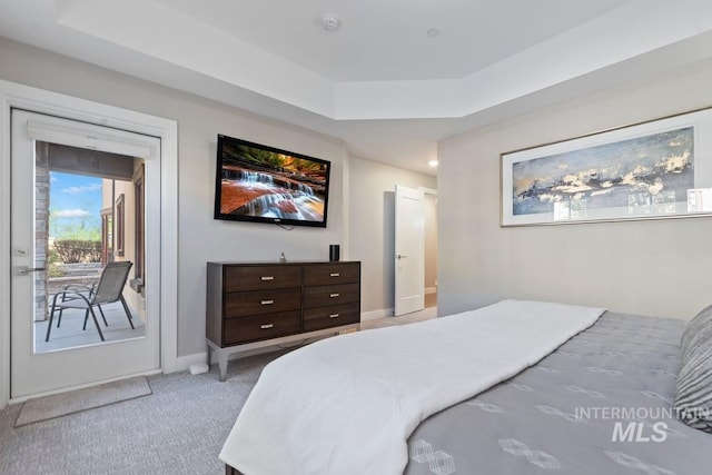 carpeted bedroom with baseboards, access to exterior, and a raised ceiling