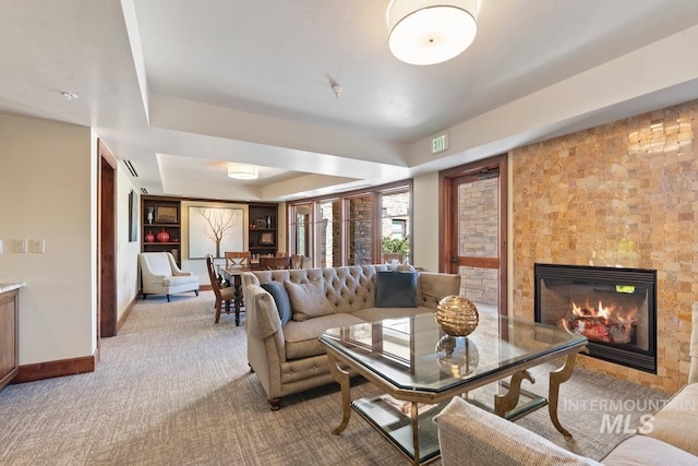carpeted living area with baseboards, a glass covered fireplace, and visible vents