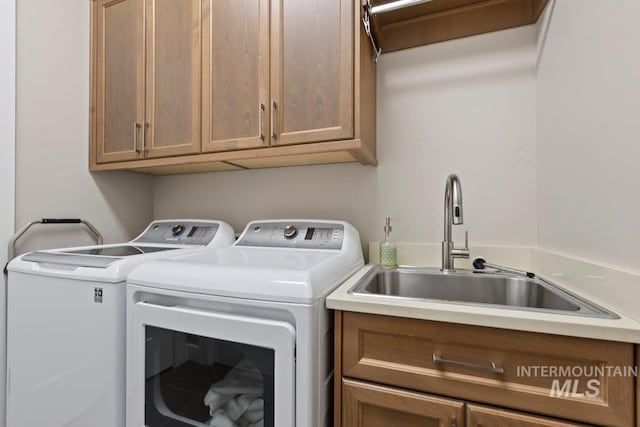 laundry room featuring washing machine and dryer, a sink, and cabinet space