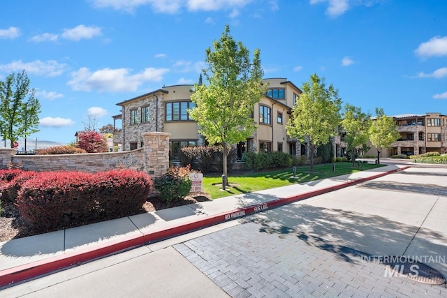 view of front of house with stone siding, stucco siding, and a front lawn