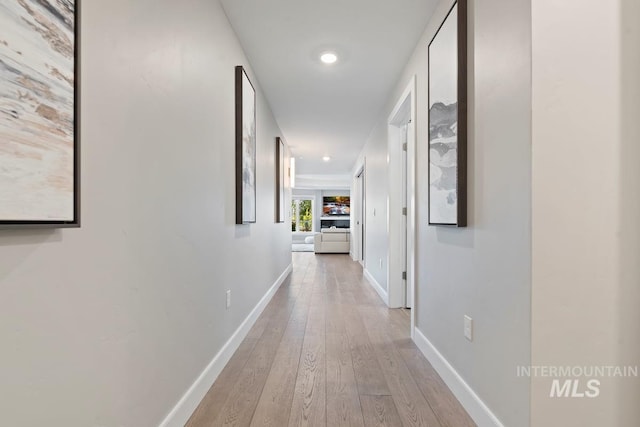 hallway with baseboards, light wood-style flooring, and recessed lighting