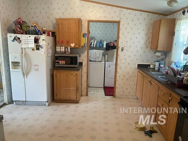 510 E Arthur Ave, Glenns Ferry, ID 83623 - kitchen featuring white fridge with ice dispenser, stainless steel microwave, washer and dryer, wallpapered walls, and light floors