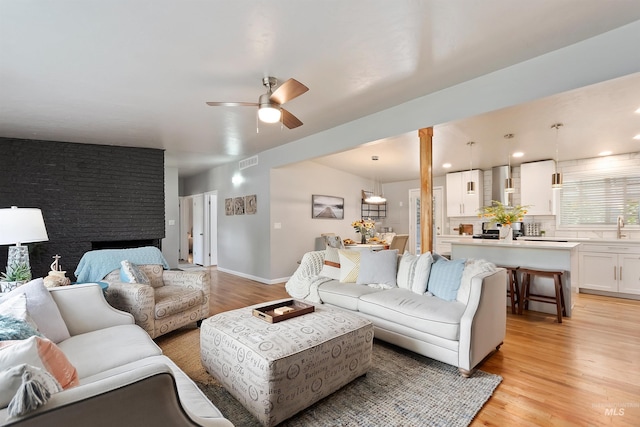 living room with light hardwood / wood-style floors, sink, and ceiling fan