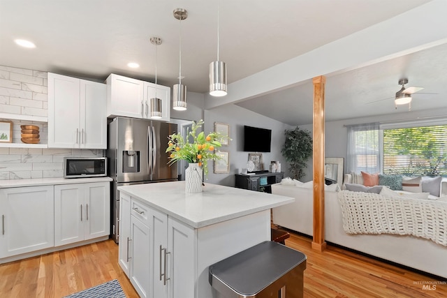 kitchen with tasteful backsplash, white cabinetry, vaulted ceiling, pendant lighting, and stainless steel appliances