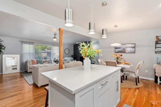 kitchen featuring light wood-type flooring, a center island, white cabinetry, ceiling fan, and decorative light fixtures