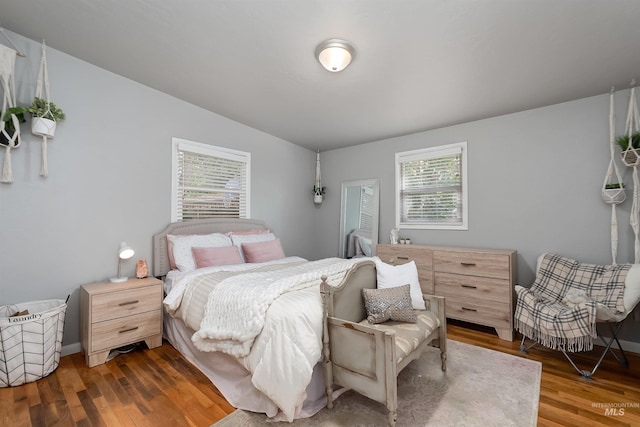 bedroom with dark wood-type flooring, lofted ceiling, and multiple windows