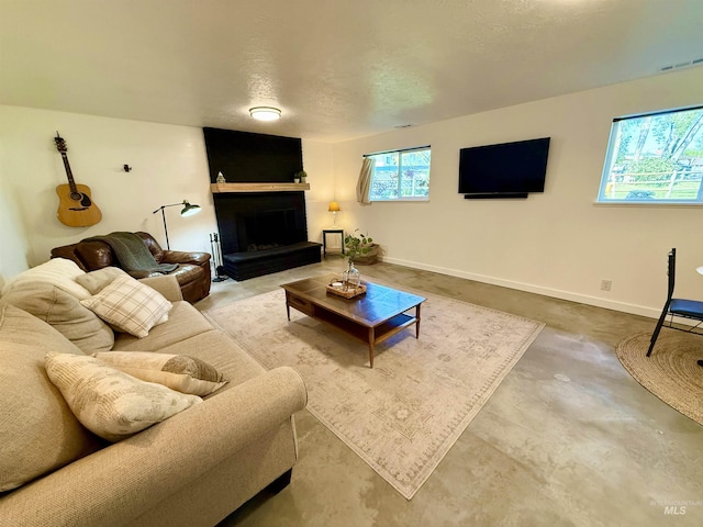 living area featuring baseboards, concrete floors, a large fireplace, and visible vents