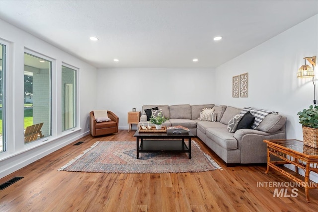living area with recessed lighting, visible vents, and light wood finished floors