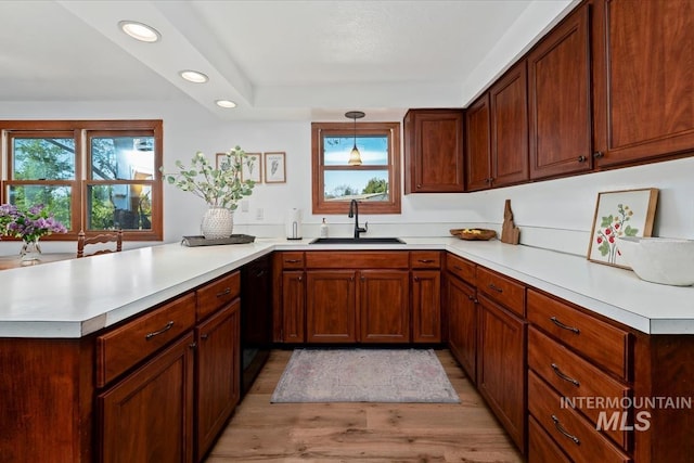 kitchen featuring a peninsula, recessed lighting, light countertops, a sink, and light wood finished floors