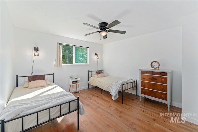 bedroom featuring baseboards, a ceiling fan, and light wood finished floors