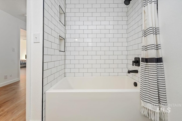 bathroom featuring baseboards, shower / tub combo with curtain, and wood finished floors