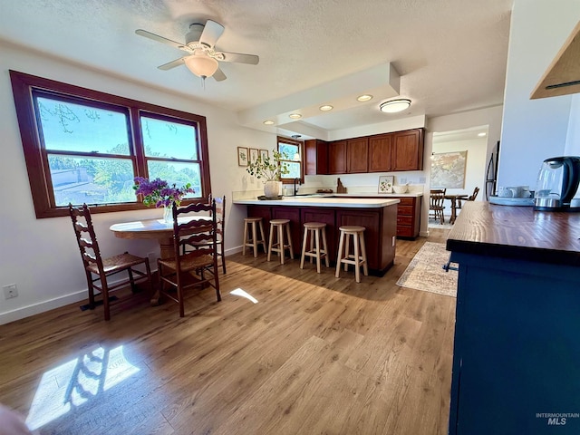 kitchen with light countertops, light wood-style floors, a breakfast bar, and a peninsula
