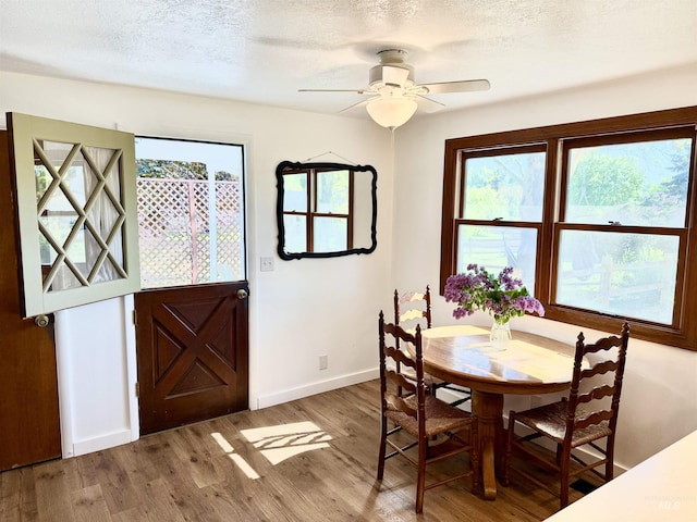 dining area with plenty of natural light, a ceiling fan, baseboards, and wood finished floors
