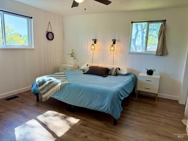 bedroom with visible vents, wood finished floors, and multiple windows