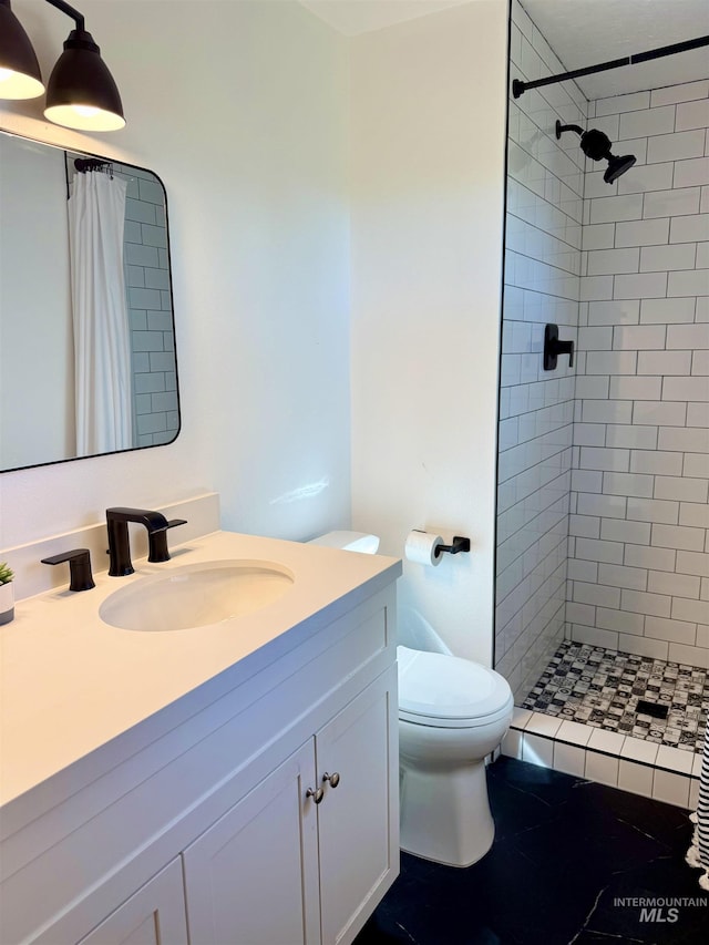 full bath featuring vanity, toilet, and tiled shower