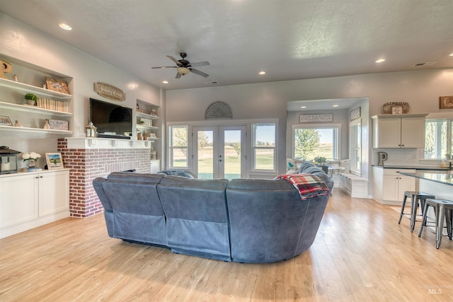 living room with ceiling fan, a brick fireplace, and plenty of natural light