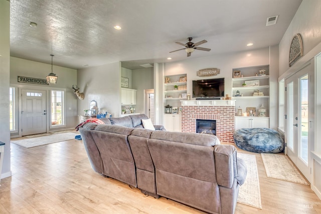 living room with a healthy amount of sunlight, ceiling fan, light hardwood / wood-style floors, and a fireplace