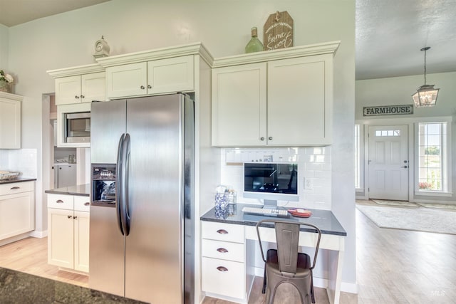 kitchen featuring pendant lighting, light wood-type flooring, stainless steel fridge with ice dispenser, decorative backsplash, and washing machine and dryer