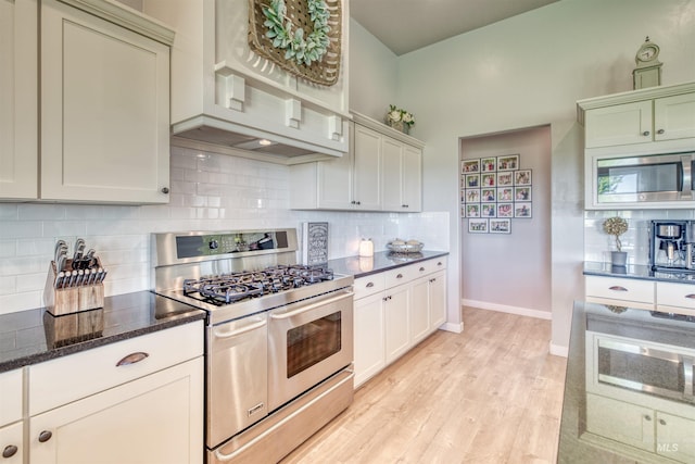 kitchen with decorative backsplash, light hardwood / wood-style floors, dark stone countertops, and stainless steel appliances