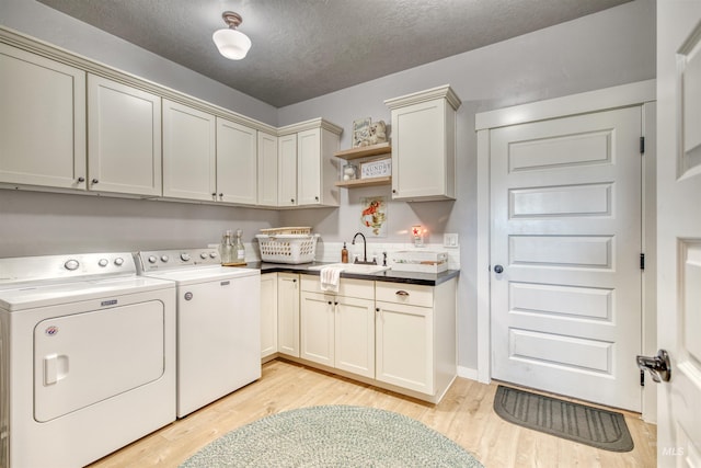 washroom featuring cabinets, a textured ceiling, light hardwood / wood-style floors, sink, and washing machine and clothes dryer