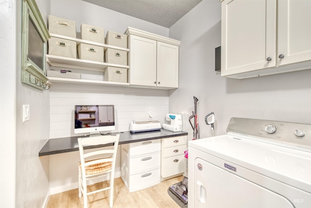 clothes washing area featuring cabinets, light wood-type flooring, and washer / clothes dryer