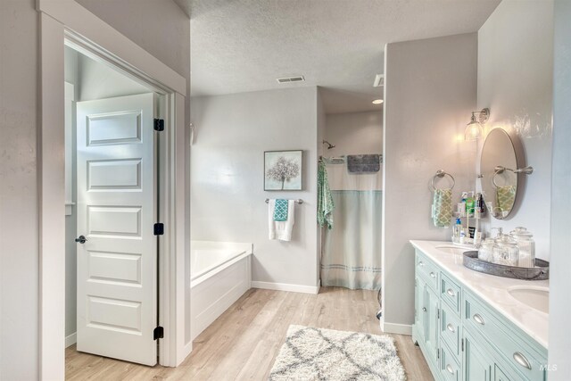 bathroom with a textured ceiling, hardwood / wood-style flooring, vanity, and separate shower and tub