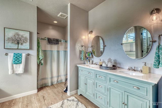 bathroom with vanity, hardwood / wood-style flooring, walk in shower, and a textured ceiling