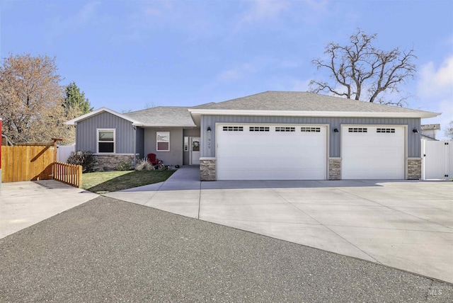 ranch-style home with an attached garage, stone siding, fence, driveway, and roof with shingles